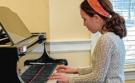 Student performing solo at a grand piano recital