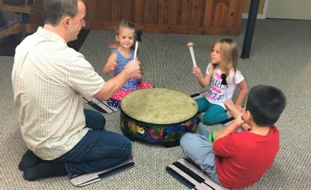 Teacher and young children playing drums together in a music lesson